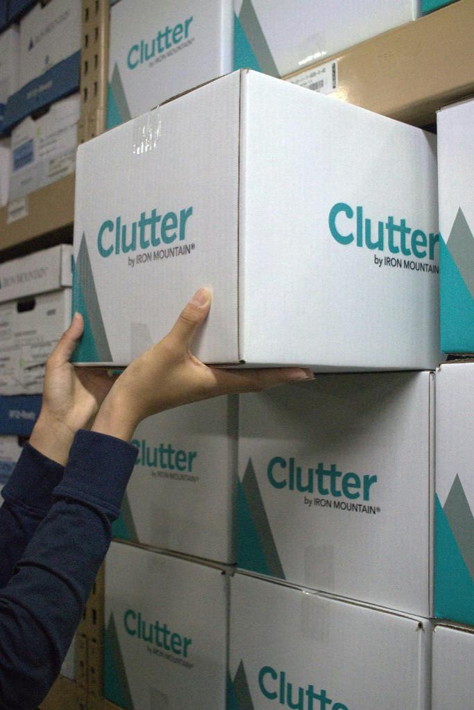 Hands placing a Clutter by Iron Mountain box in a secure warehouse